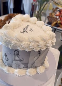 a white cake with pictures on it sitting on top of a table next to other desserts