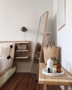 a room with a bed, mirror and shelf on the floor next to a window