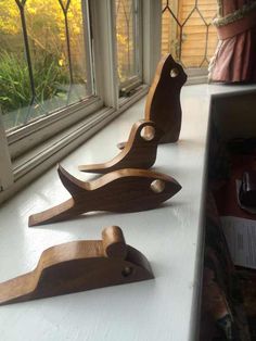 three wooden birds sitting on top of a white counter next to a window sill