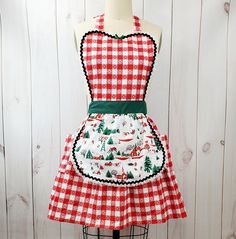 a red and white christmas apron on a mannequin stand with a green belt