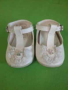 pair of white baby shoes on green background