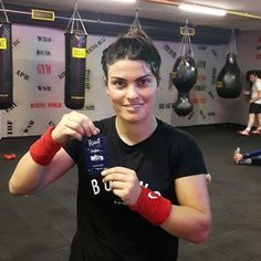 a woman in a boxing ring holding up a bottle of boojute while wearing red gloves