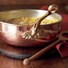 a metal bowl filled with food on top of a wooden table