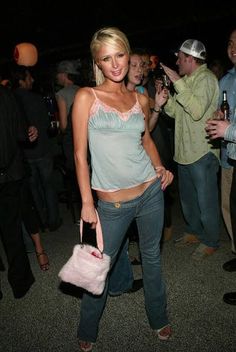 a woman holding a pink purse standing next to other people at a party or gathering