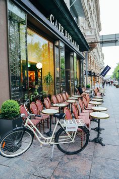 there are many tables and chairs outside of the restaurant with bikes parked on the sidewalk