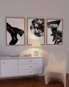 a white chair sitting in front of two pictures on the wall