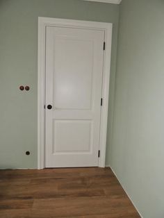 an empty room with a white door and hard wood floor