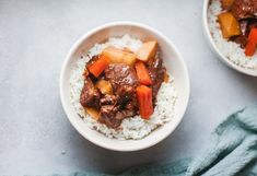 two bowls filled with rice and beef on top of a table next to a blue towel