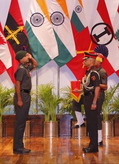 two men standing in front of flags on a stage with one man saluting the other