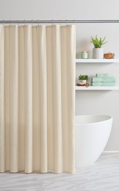 a bathroom with a white tub and shower curtain next to a shelf filled with towels