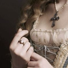 a woman in a dress with a cross on her chest and ring around her neck