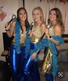 three women dressed in blue and gold holding spoons