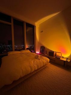 a large bed sitting in a bedroom next to a window with city lights on it