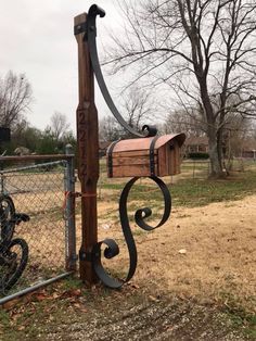 a mailbox attached to a wooden post by a chain link fence with a bicycle parked in the background