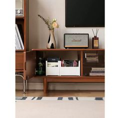 a tv is mounted on the wall next to a shelf with books and other items