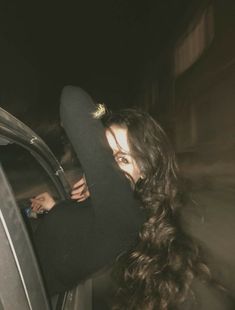 a woman with long hair leaning out the window of a car