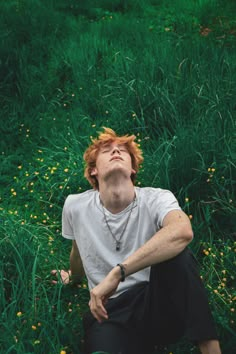 a man laying in the grass with his eyes closed and head tilted to the side