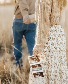 a man and woman holding hands while standing in tall grass