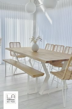 a wooden table with four chairs and a white vase filled with flowers sitting on top of it