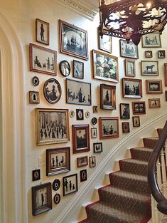 a staircase with many pictures on the wall and a chandelier hanging above it