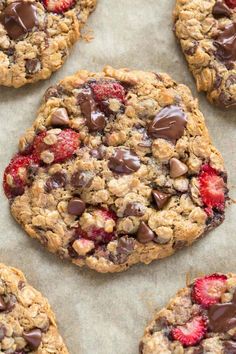 cookies with chocolate chips and strawberries are on a baking sheet, ready to be eaten