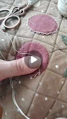 someone is stitching on the fabric with scissors