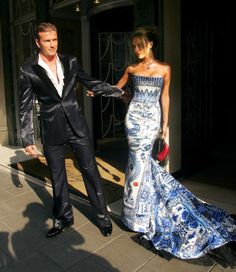 a man in a tuxedo walking next to a woman in a blue dress