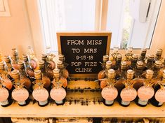 a table topped with lots of bottles filled with liquid next to a sign that says from miss to mrs