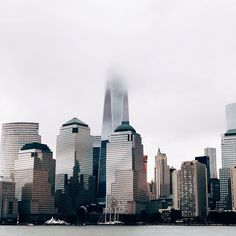 the city skyline is covered in fog and smoggy clouds as seen from across the water