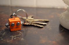 two keys are attached to an orange robot keychain