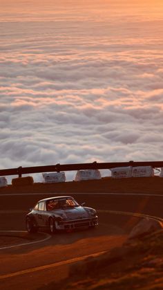 a car driving down a road surrounded by clouds