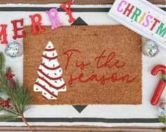 a christmas door mat with the words merry to the season on it and decorations around it