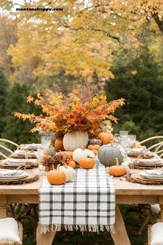 a table set with pumpkins and other autumn decorations