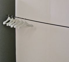 four white hangers are hanging on a black line in front of a white wall