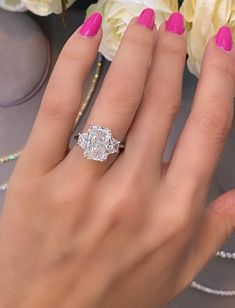 a woman's hand with pink manicured nails and a diamond ring on her finger