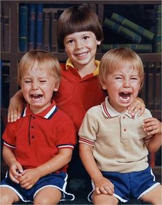 three young boys sitting next to each other with their mouths open in front of them