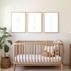 a baby's crib with two pictures on the wall above it and a teddy bear