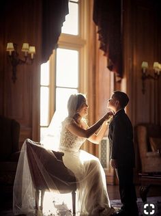 a young boy helping his bride put on her wedding dress in the sunlit room