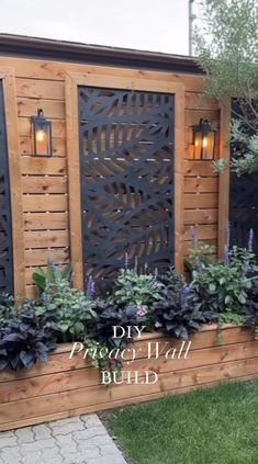 a wooden fence with plants and lights on it in front of a building that says diy privacy wall build