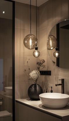 a white bowl sitting on top of a counter next to a mirror and light bulbs