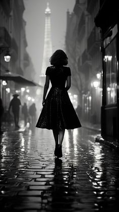 a woman is walking down the street with an umbrella in her hand while looking at the eiffel tower