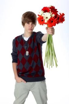 a young man holding flowers in his hand