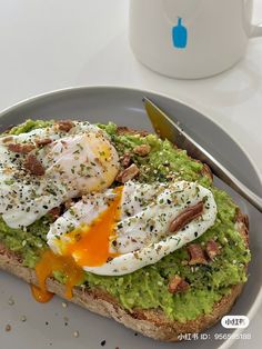 an open face sandwich with avocado and poached eggs on it next to a cup of coffee