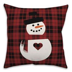 a red and black plaid pillow with a snowman in the center on top of it