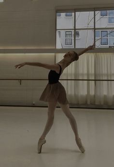 a young ballerina is practicing in an empty room