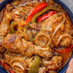 a bowl filled with meat, onions and peppers on top of a table next to a person's hand