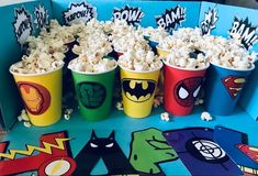 popcorn buckets filled with white chocolate and topped with sprinkles are sitting on a table