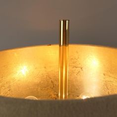 two gold colored candles sitting in a metal bowl