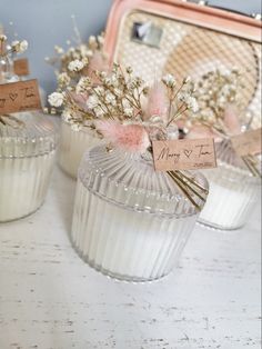 three small glass vases with flowers in them on a white counter top next to a purse