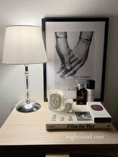 a lamp and some books on a small table with a poster above it that says film for her